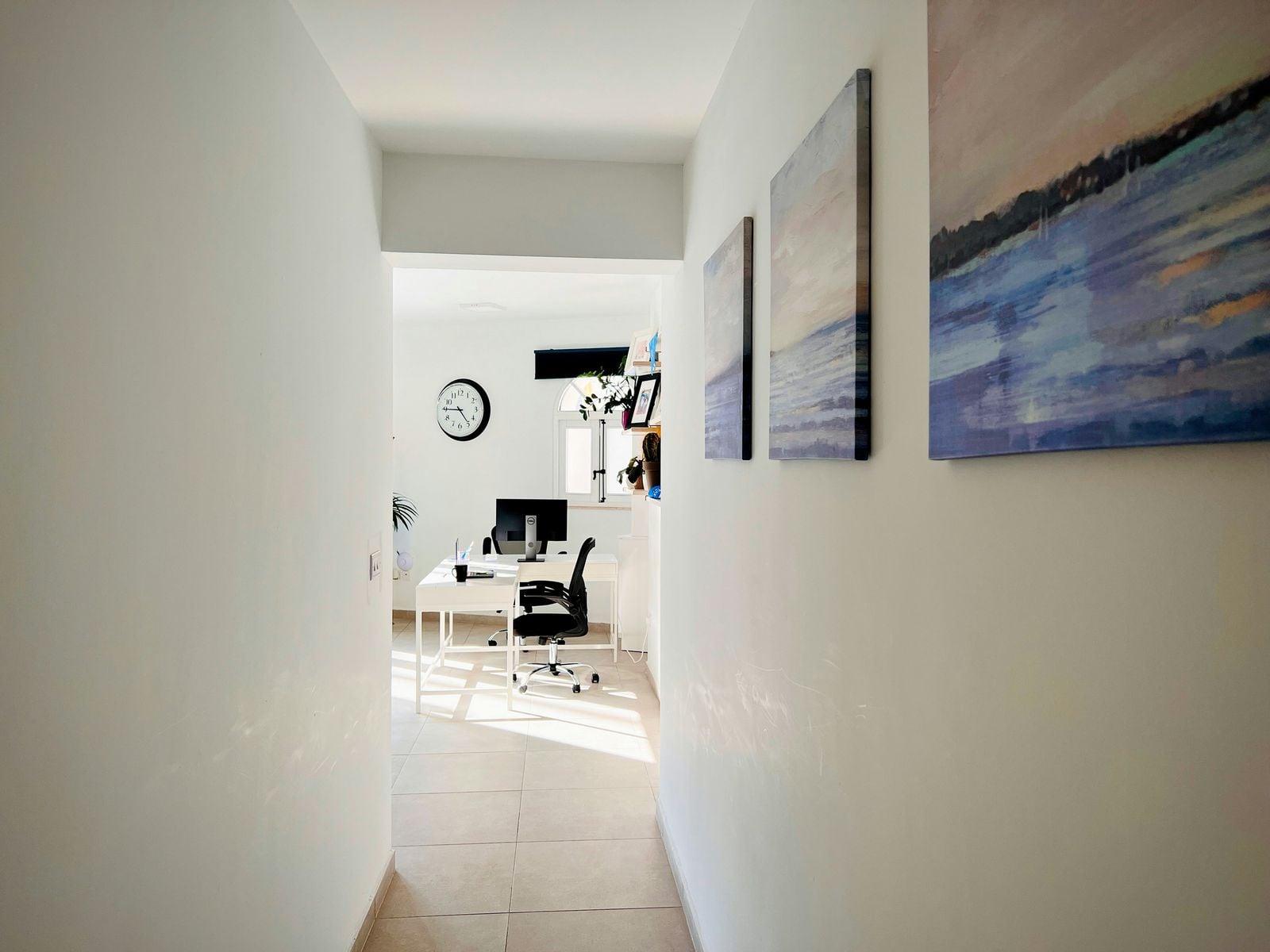 Hallway leading to a bright office with artwork