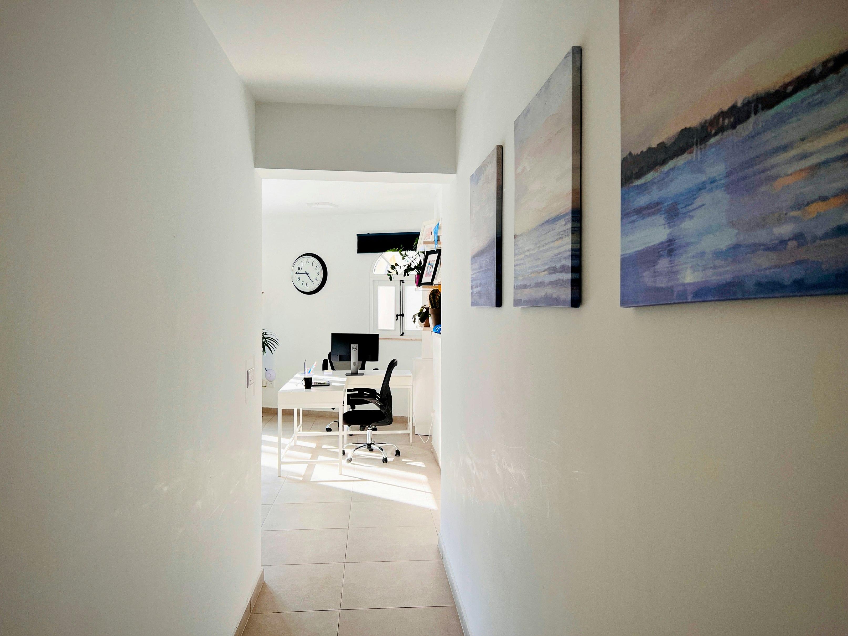 Hallway leading to a bright office with artwork